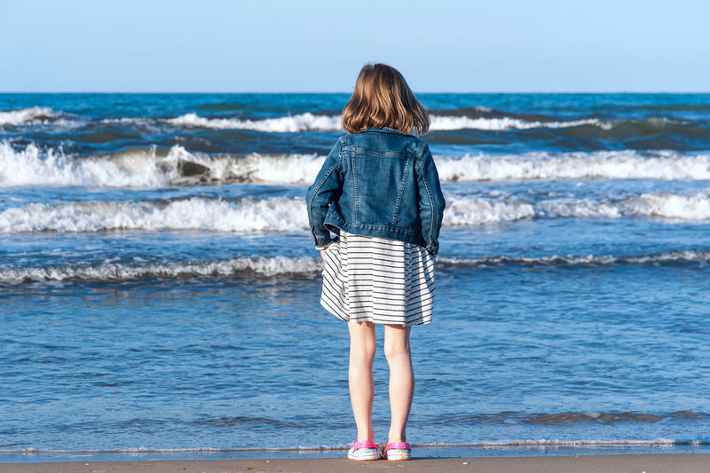 Rear view of girl standing at beach