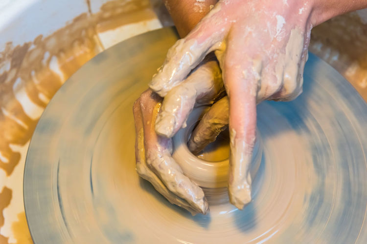 Cropped hands of potter molding clay