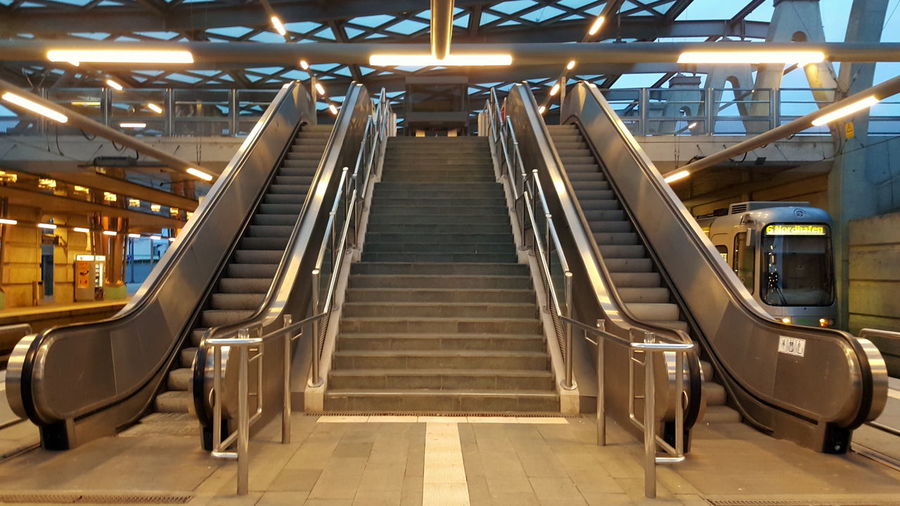 Low angle view of staircase amidst escalator in modern railroad station