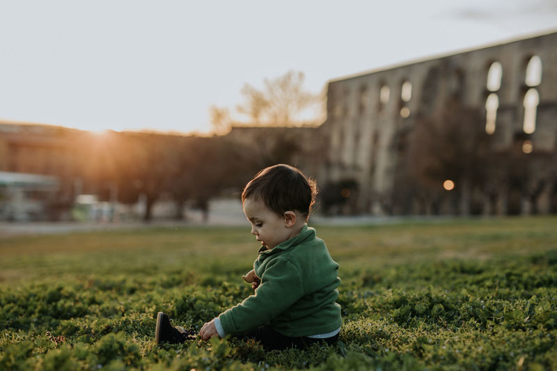 Side view of a boy sitting on field