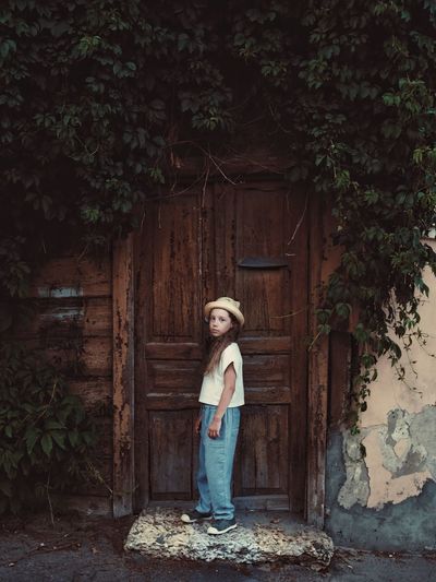 Portrait of girl standing against old door 