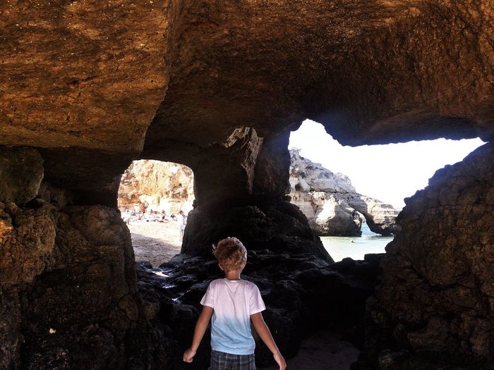 Rear view of boy standing in cave