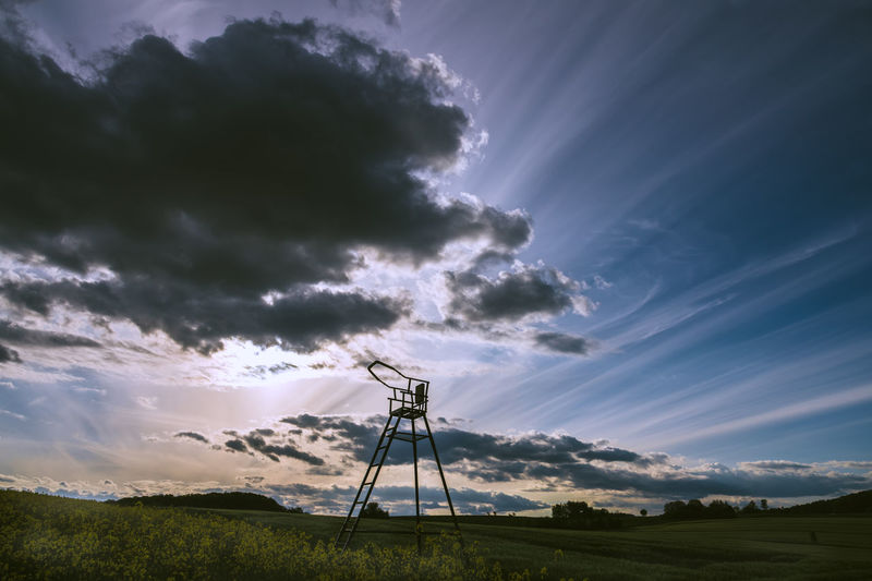 Low angle view of silhouette windmill on field against sky