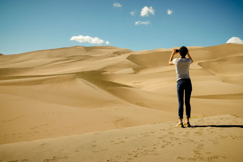 Rear view of young woman photographing desert
