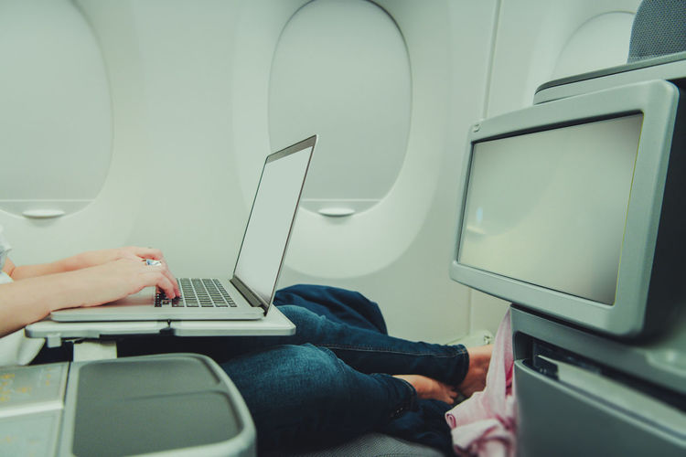 Caucasian woman remotely working on her laptop computer while in airplane business class
