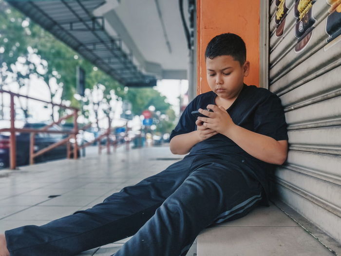 Young man using mobile phone while sitting 