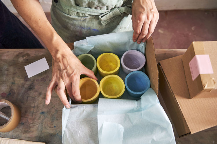 Female store owner arranging colorful design concretes in box at workshop