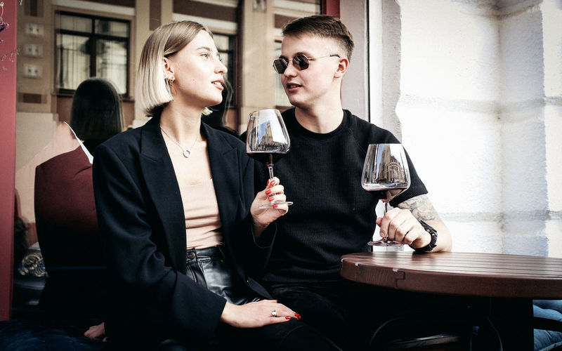 Young couple holding wineglass sitting at restaurant