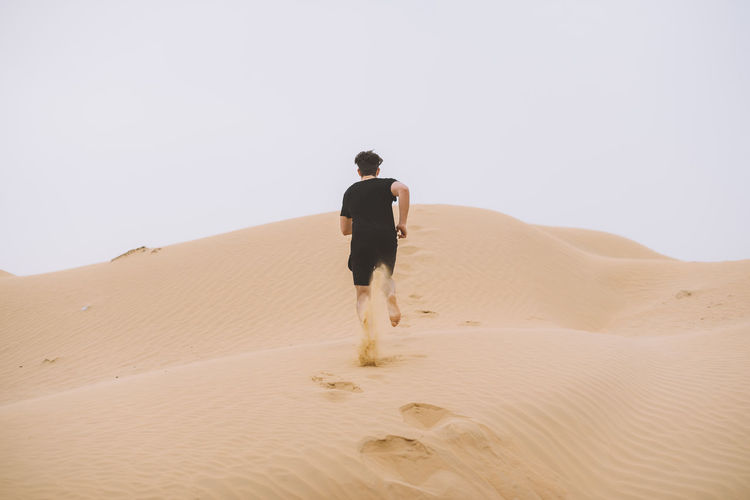 Rear view of man on sand dune in desert