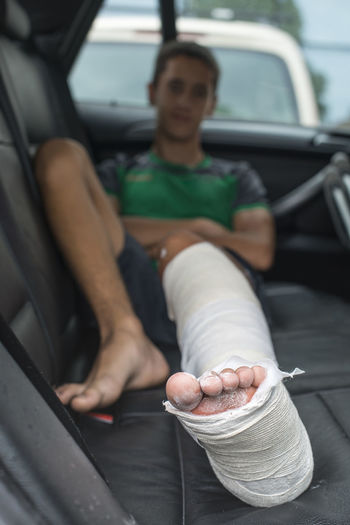Boy with broken leg sitting in car