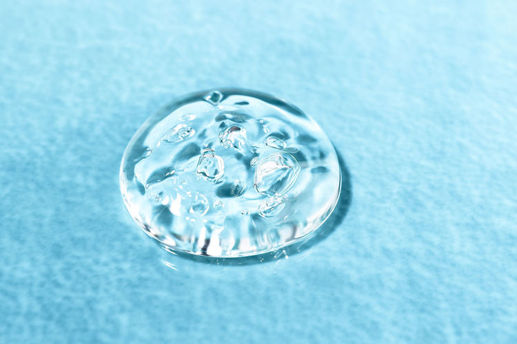 A drop of transparent body care cosmetic product, spa treatments on a colored background