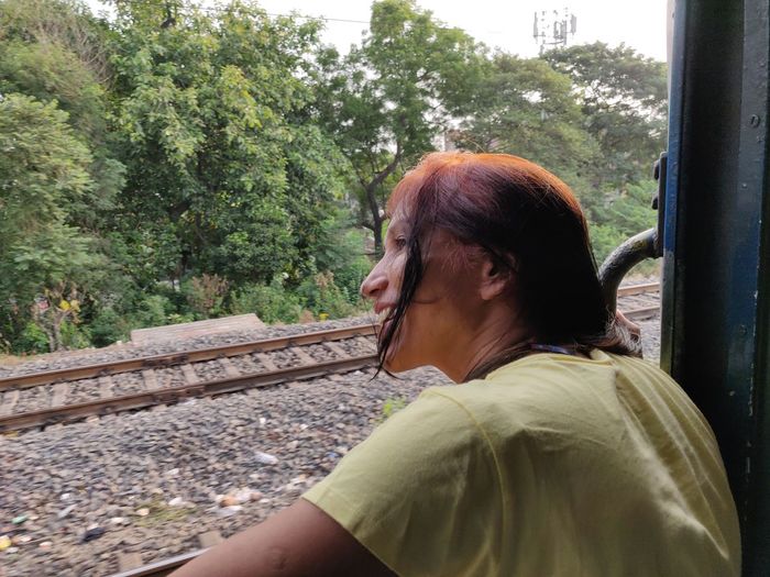 Side view portrait of mature woman sitting on railroad track