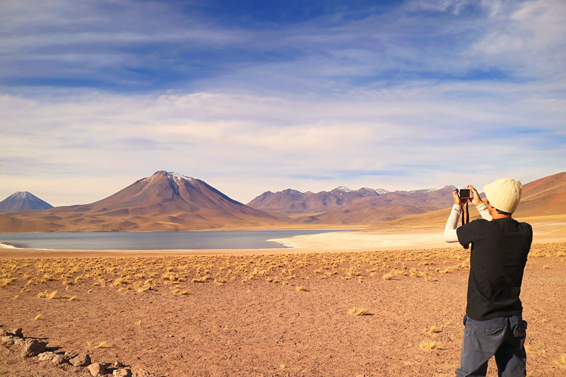 Visitor shooting photos of miscanti lake with mt. cerro miscanti in the backdrop, chile