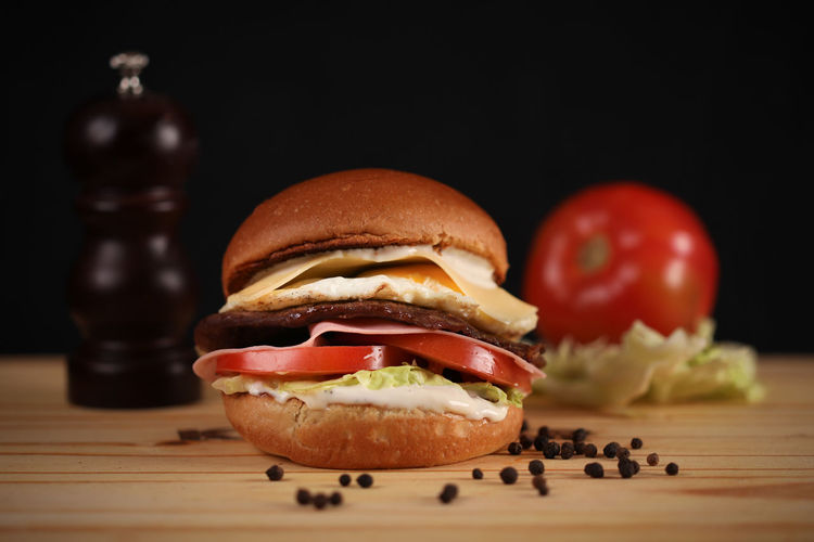 Close-up of burger on table against black background