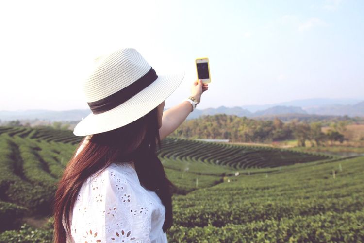 Side view of woman photographing farm through smart phone