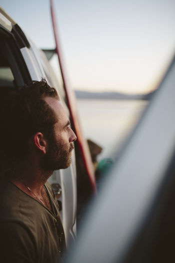 Close-up of thoughtful man looking away against off-road vehicle