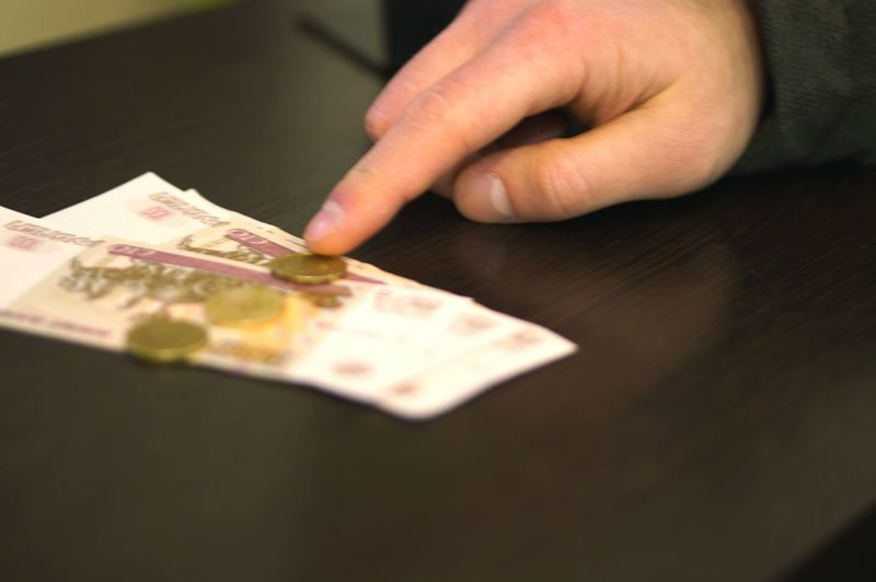 Cropped hand of child touching currency on table