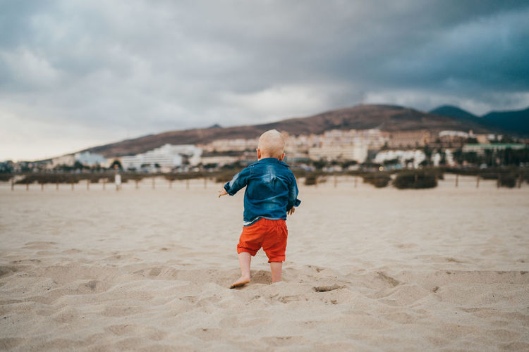 Boy playing at the beach on a cloudy and cold day
