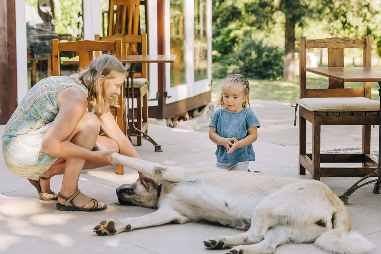 Mother and daughter playing with dog on floor