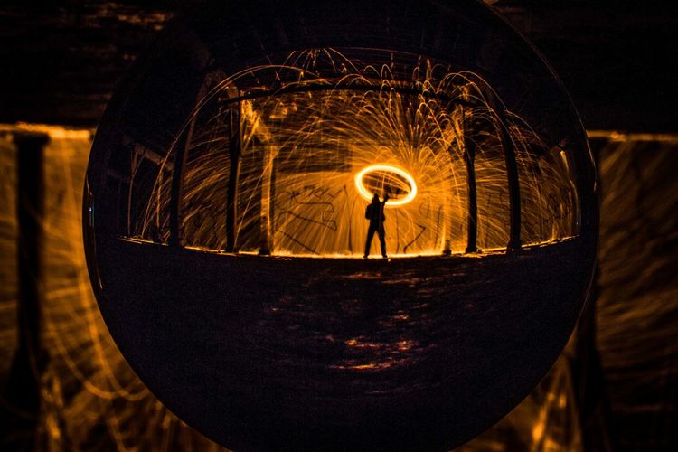 Upside down image of man with wire wool reflection on glass ball