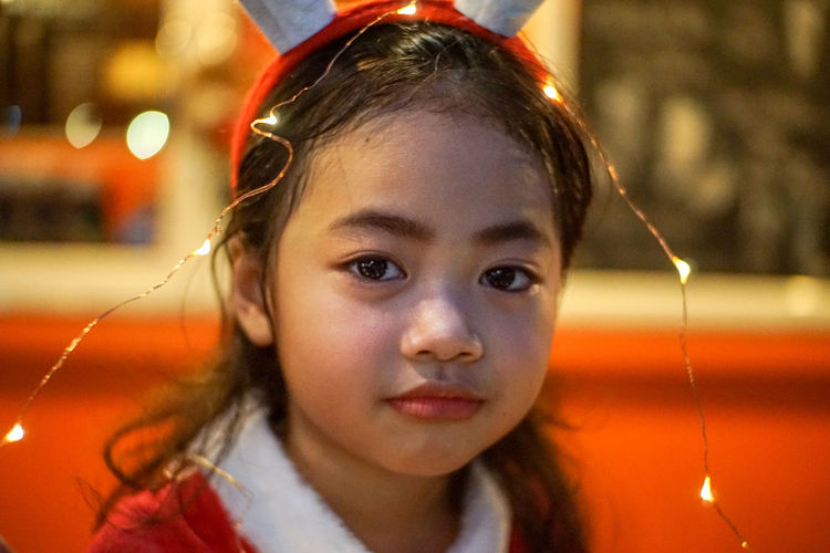 Close-up portrait of cute girl with string lights