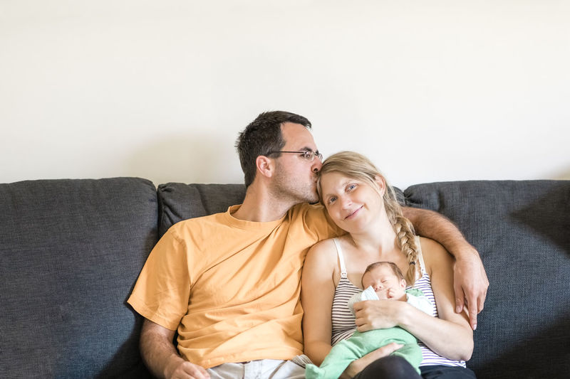 Portrait of smiling woman sitting with husband and baby at home