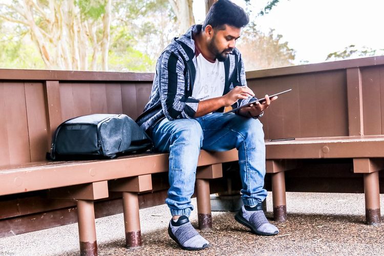 Young man using mobile phone while sitting on seat