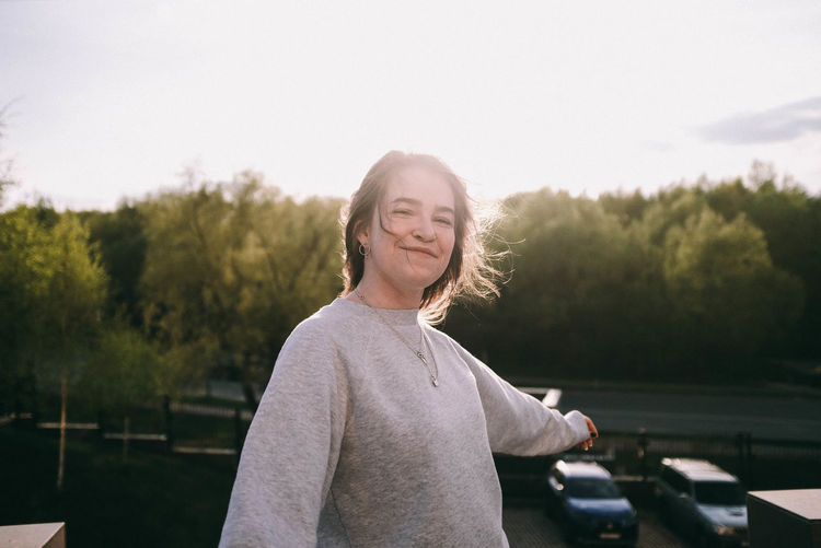 Portrait of smiling woman standing against trees