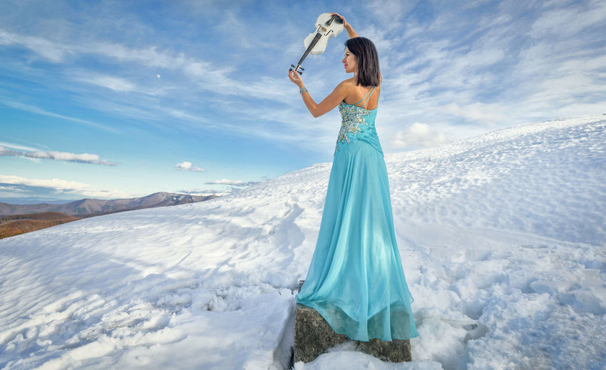 Woman standing on snow covered landscape against sky