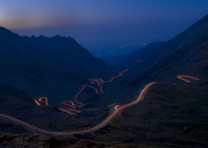 Light trails on mountain against sky at night