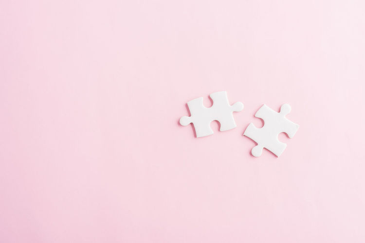 High angle view of jigsaw pieces on pink background