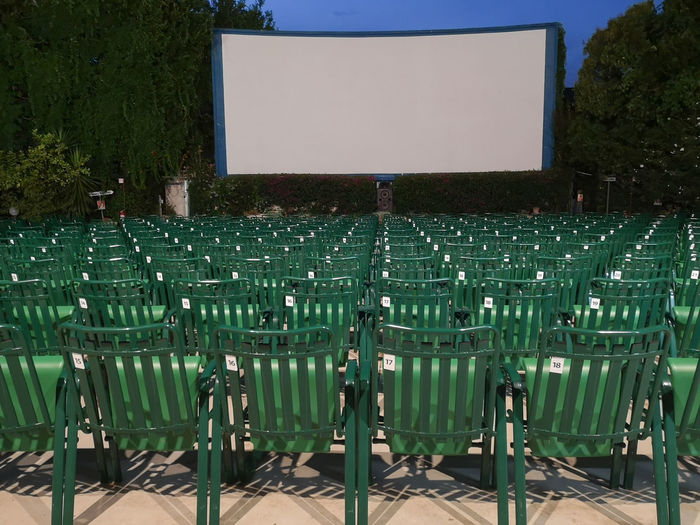 Outdoor cinema- empty green seats and white screen.