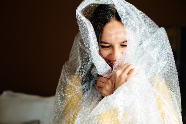 Girl wearing bubble wrap sitting at home