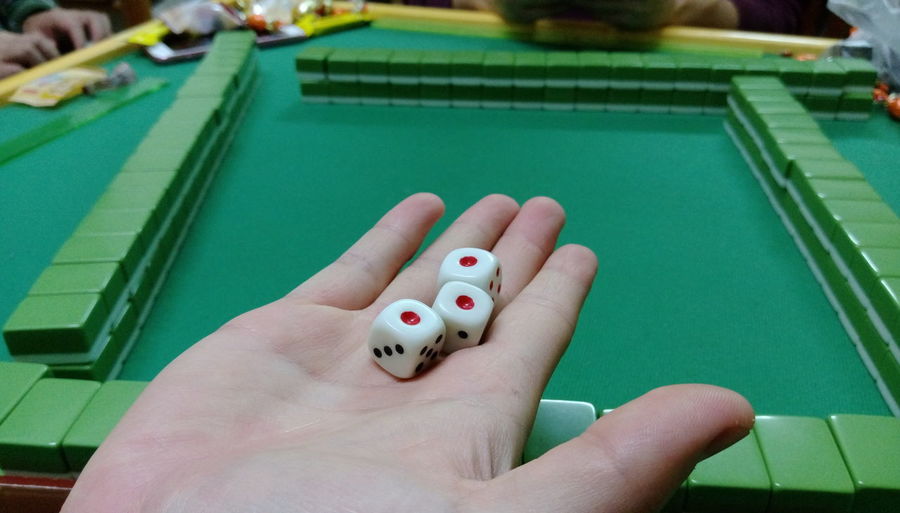 Cropped image of hand holding dices while playing mahjong