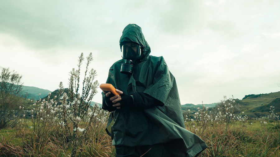Military walking with geiger counter in a contaminated field