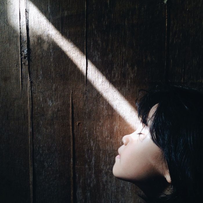 Sunlight falling on girl against wooden wall