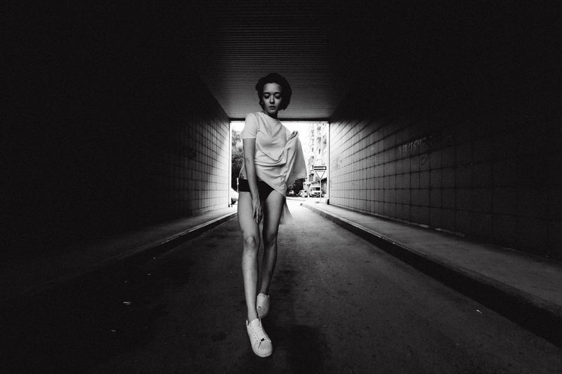 Full length portrait of young seductive woman in tunnel
