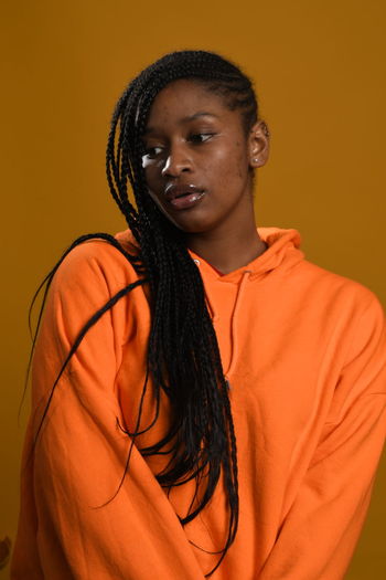 Portrait of teenage girl standing against orange background