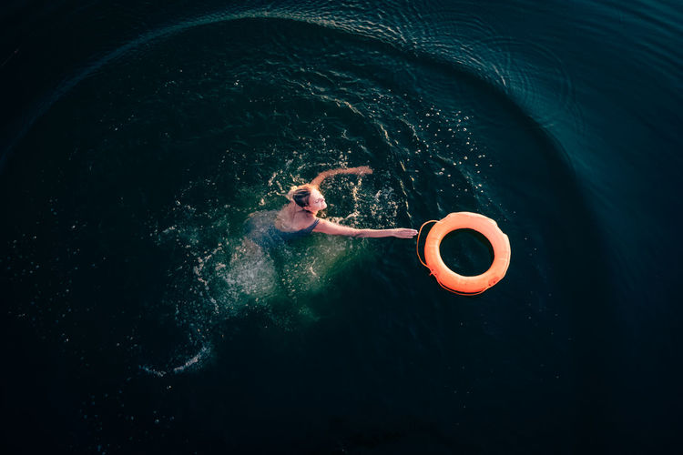 High angle view of woman touching pool raft in sea