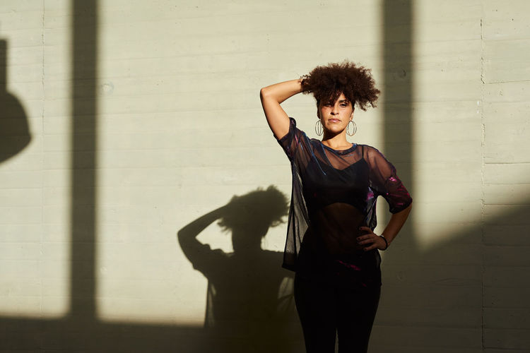 Portrait of a young woman with afro hair, her shadow is projected behind