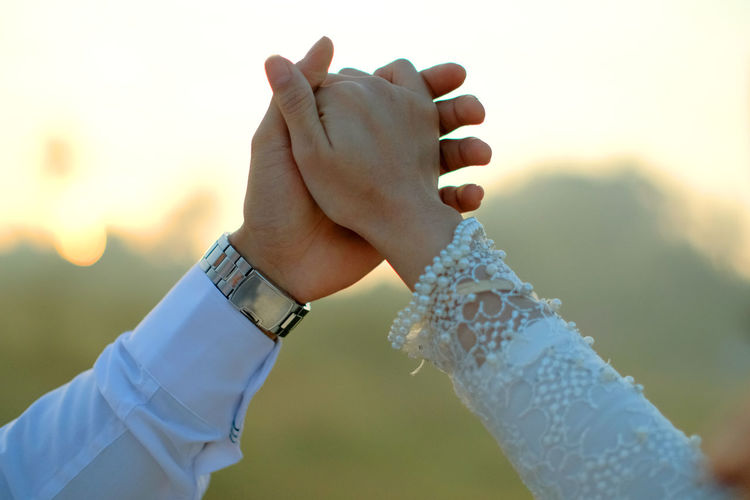Midsection of woman and man holding hands against blurred background