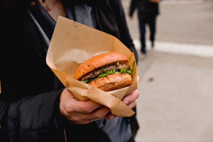 Midsection of woman holding burger at street