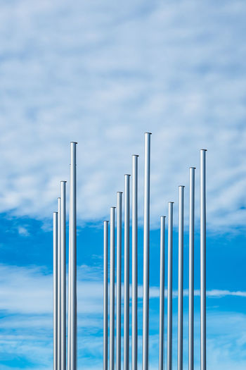 Low angle view of flagpoles against blue sky