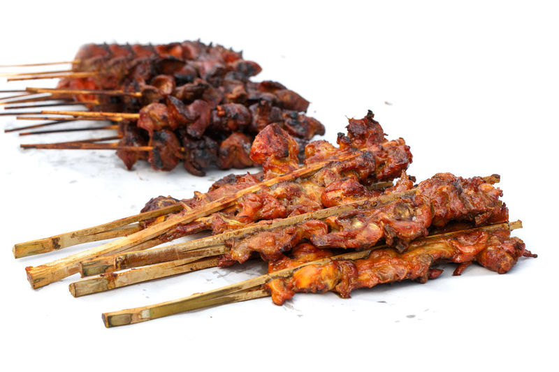 Close-up of meat on barbecue grill against white background