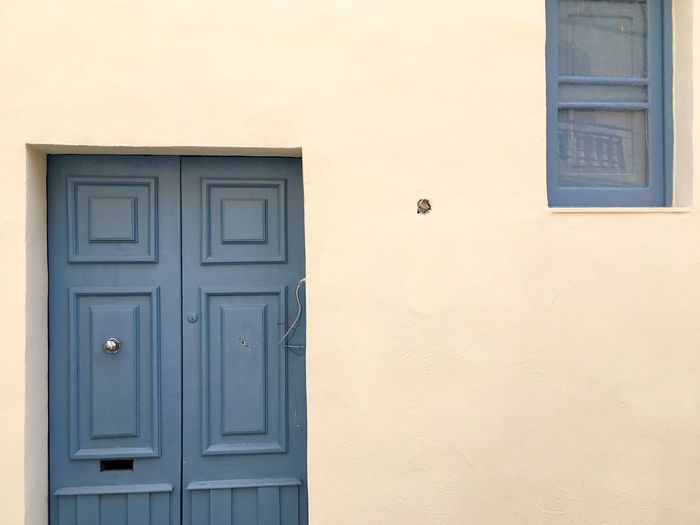 Closed gray door and window amidst beige wall