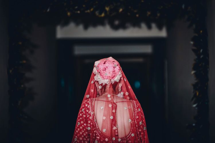 Rear view of bride wearing flowers while standing at doorway