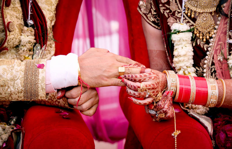 Midsection of bride putting ring in groom finger during wedding ceremony