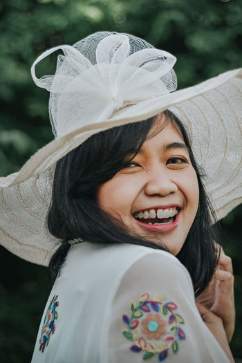 Close-up portrait of cheerful young woman wearing hat