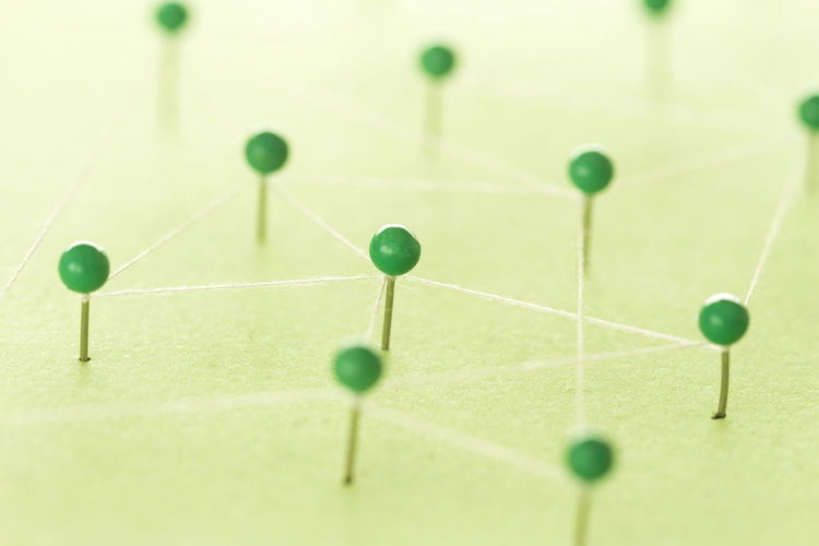 Close-up of strings connected with green straight pins on table