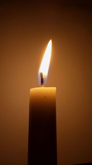 Close-up of lit candle against black background